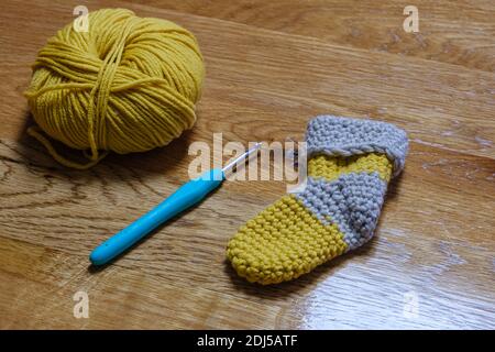 Handmade wool sock on a wooden table with crochet hook. Stock Photo