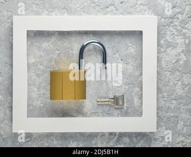 Lock and keys in a white frame on a gray concrete background. Minimalist trend. Stock Photo