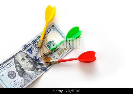 investing with darts in yellow, green and red colors on a white background and 100 US dollars, and dollars for an accurate investment, Stock Photo