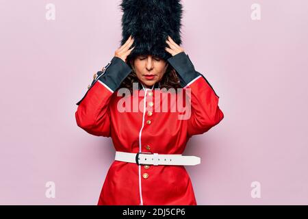 Middle age beautiful wales guard woman wearing traditional uniform over pink background suffering from headache desperate and stressed because pain an Stock Photo