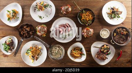 Top view of a table full of various meals for vegetarians and meat eaters served on plates and in pans. Stock Photo