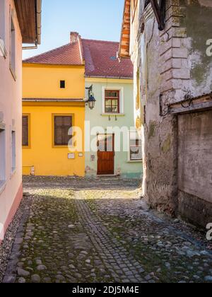 Colorful scene with cobblestone streets and old buildings of Sighisoara Medieval Fortress, in Romania. Stock Photo