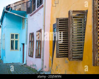 Close up detail with old colorful painted homes and wooden windows shutters in the Sighisoara Citadel, Romania. Stock Photo