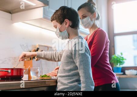 Mother and son cooking at home during the crisis time Stock Photo