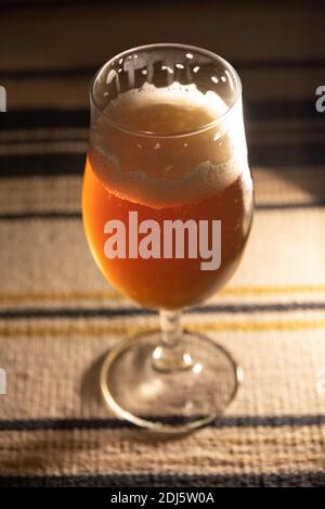 A glass of delicious looking craft beer on a table, waiting to be consumed. Stock Photo