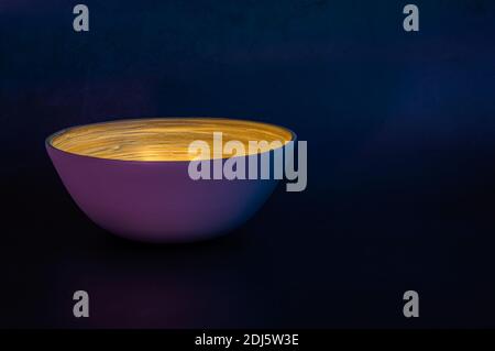 Image of a bamboo bowl filled with light in a dark environment with blue and purple tones Stock Photo