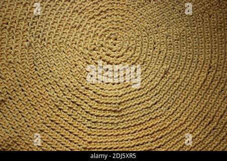 Wrinkled texture of golden yellow crochet handmade rug made of cotton. Small handmade business concept. Stock Photo