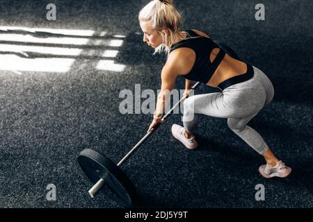 Strong fitness woman, in sportswear, trains with heavy weights in the gym, Sportswoman lifts the barbell in the gym. Stock Photo