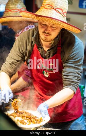 Manchester December 2020. Christmas street markets selling food nr Piccadilly Gardens. A man interacting with a customer ordering food Stock Photo