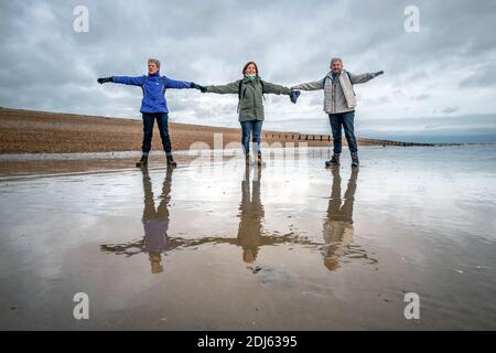 Rye Harbour, December 12th 2020: Three friends pose for a photograph on Winchelsea Beach Stock Photo