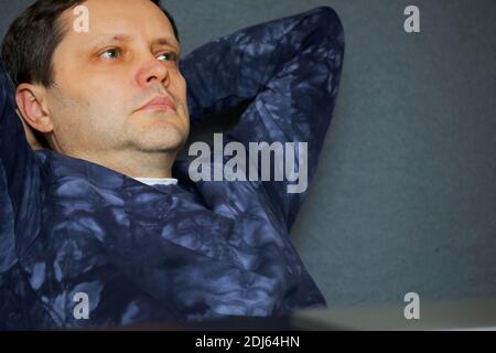 Portrait of a man with hands behind his head. Sits with a pensive look. Close-up shot. Stock Photo