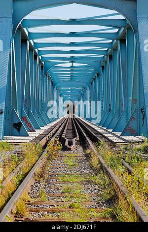 Blue steel railroad bridge with dual gauges at the national border between Sweden and Finland. Stock Photo