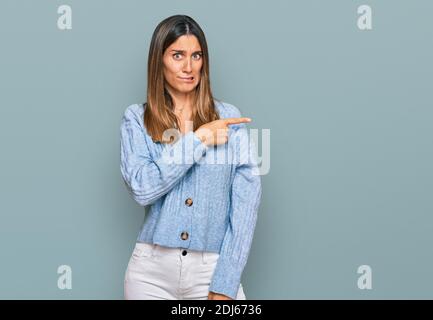 Young woman wearing casual clothes pointing aside worried and nervous with forefinger, concerned and surprised expression Stock Photo