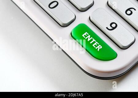 Close up view of the Enter key on an electronic calculator on a plain white background. No people, Copy space. Stock Photo