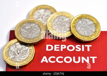 Close up of a savings deposit book with one pound coins. No people. Copy space. Stock Photo