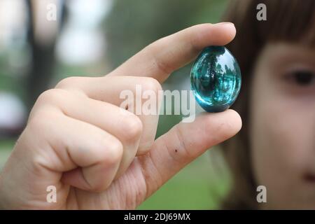Crystal glass ball in human hand on defocused grass background. Saving environment, save clean green planet, ecology concept. Stock Photo