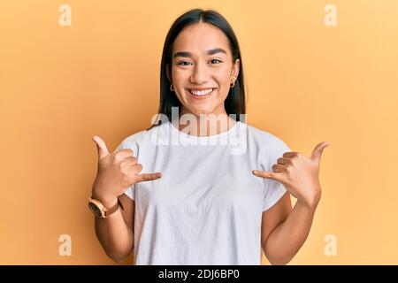 Young asian woman doing shaka sign with hands smiling with a happy and cool smile on face. showing teeth. Stock Photo