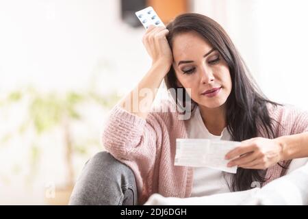 Worried expression on a face of a woman reading a label of medication packaging. Stock Photo