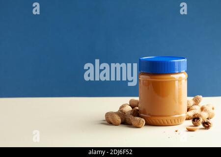 closed jar of peanut butter, peanuts in their shells. American culture. Breakfast, dessert for vegetarians. Copy space. Stock Photo