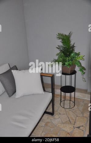Corner of the balcony with modern two-seater and plant. Illustration of a sofa on a shiny stone floor with a plant. Stock Photo