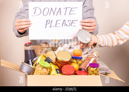 Volunteers collect grocery products to food donation box and holding paper sheet with message Thank you Stock Photo