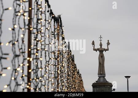 Constance, Germany - 11 28 2020: Imperia statue, a landmark with Christmas decoration around it. There are chains of lights like tiny golden spots. Stock Photo