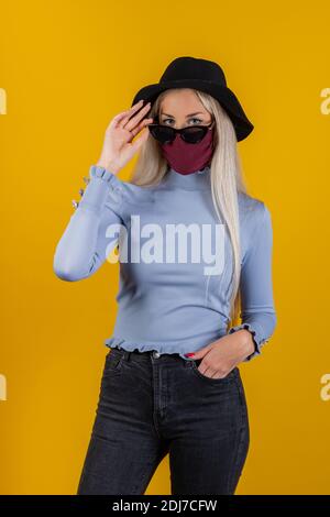 Woman wearing trendy fashion outfit and during quarantine of coronavirus outbreak. Model dressed protective stylish handmade face mask, black sunglass