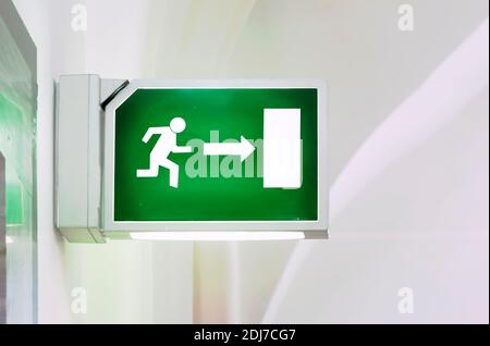 Illuminated green emergency exit sign. Stylized human figure running towards a door. Security and infographics Stock Photo