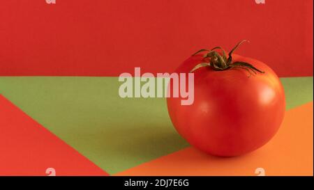 red tomato with green stem, on red background, on orange background, on green background, concept, copy space Stock Photo