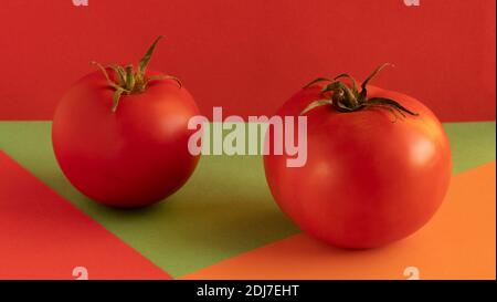 red tomato with green stem, on red background, on orange background, on green background, concept, copy space Stock Photo