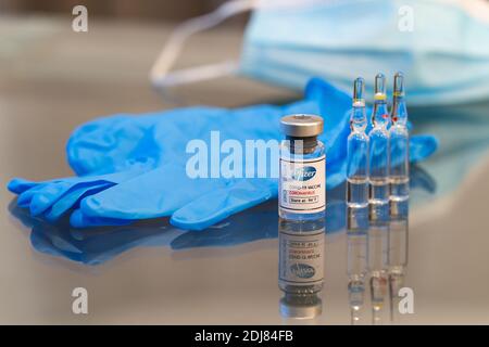 LONDON, ENGLAND - DECEMBER 13, 2020:  A Glass vial containing the Pfizer BioNtec COVID-19 Coronavirus vaccine solution ready for use with 3 glass ampo Stock Photo