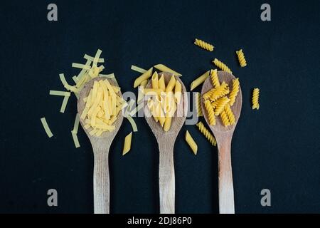 Different types of Italian pasta in spoon on the black background Stock Photo
