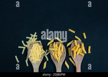 Different types of Italian pasta in spoon on the black background Stock Photo