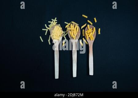 Different types of Italian pasta in spoon on the black background Stock Photo