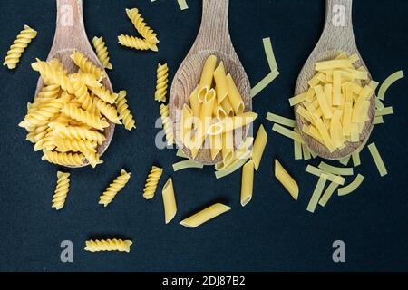 Different types of Italian pasta in spoon on the black background Stock Photo