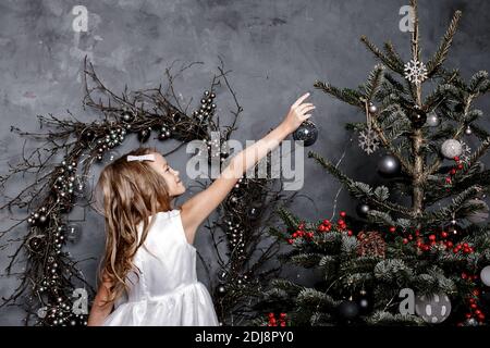Child daughter decorate Christmas tree at home. Preparing home for New Year party, family enjoying winter holiday. Family, winter holiday and people c Stock Photo
