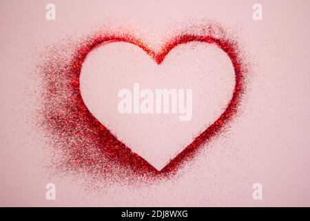 Happy Valentine's Day. Red heart made of glitter on a pastel pink background Stock Photo