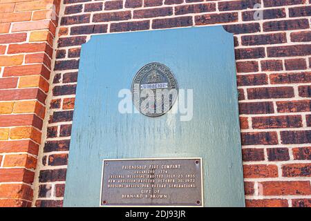 Alexandria, VA, USA 11-28-2020: A metal information plate attached to the brick exterior wall of the Friendship Fire Company, the first fire station d
