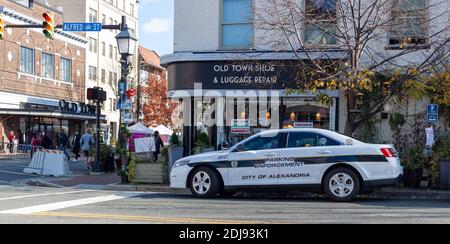 Alexandria, VA, USA 11-28-2020: A view of downtown Alexandria with shops and people on street. A white police car used by Parking Enforcement Officers