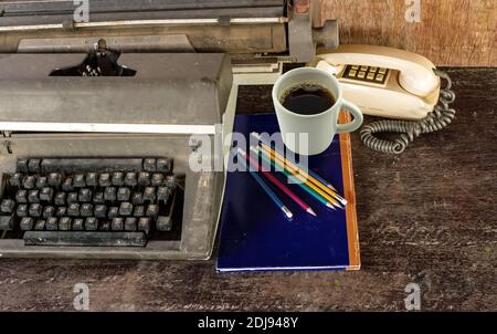 Vintage typewriter ,blue  book,  ,pencil and old telephone on old wooden touch-up in still life concept Stock Photo