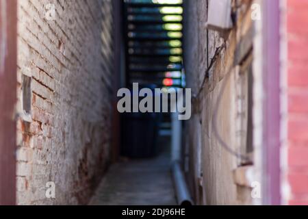 An abstract out of focus image of a narrow alley between brick walls of two vintage buildings at an urban location. The paint on walls is chipped, the