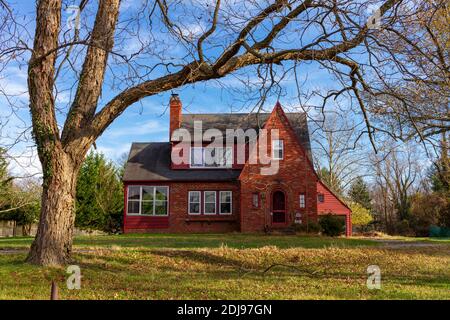 Rockville, MD, USA 11-10-2020: A two story red brick vintage  house in a spacious land with a tall tree on its front yard.  A good example of an histo Stock Photo