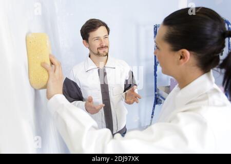 female builder using sponge on wall Stock Photo