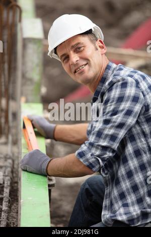 smiling builder using a spirit level on a construction site Stock Photo