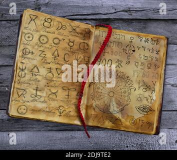 Old witch book with alchemic symbols, open book with magic spells, occult and mystic background. Stock Photo