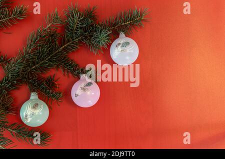 Christmas tree branches decorated by colorful balls on the red sparkled background. Christmas, New Year, winter holiday.