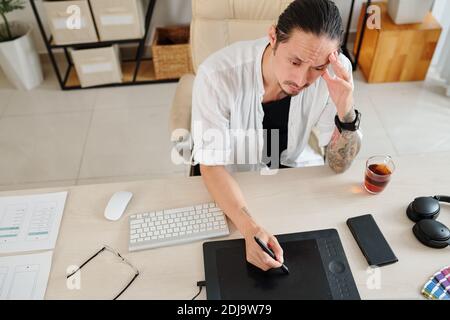 Frowning designer suffering from lack of inspiration when working on project for client Stock Photo