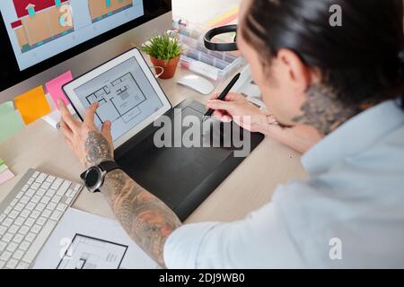 Cropped image of graphic designer checking construction plan on tablet computer when drawing 3D sketch of house interior design Stock Photo