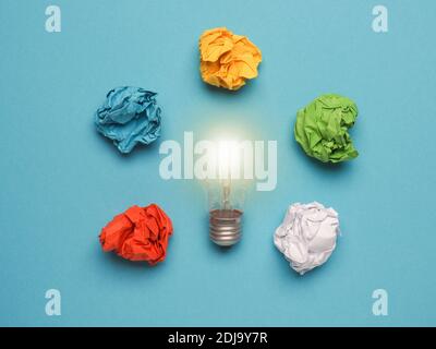 Light bulb with colorful crumpled paper balls on a blue background, great ideas concept, creativity, mindset, power Stock Photo