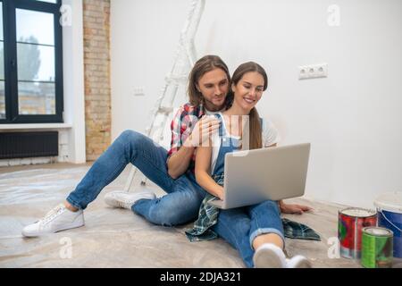 Young couple sitting on the floor and searching for something online Stock Photo